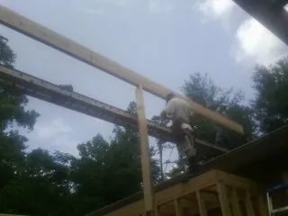 Carpenter setting a ridge beam over a new addition frame — Ice Dam Removal by Roofing Brothers in Manlius