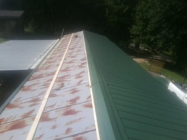 Old rusted panels beside newly installed green metal roofing — Wind Damage Roof Repair by Roofing Brothers in Manlius