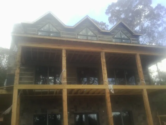 Dormers and porch framing on a large log home under construction — Roof Coating work by our crew in Manlius