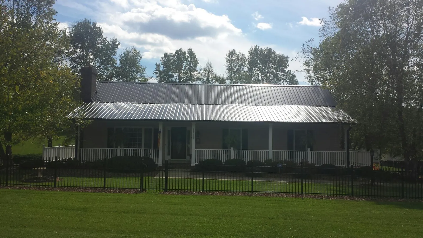 Gray metal roof on a brick ranch with a full width front porch — Gutter Guard Installation work by our crew in Manlius
