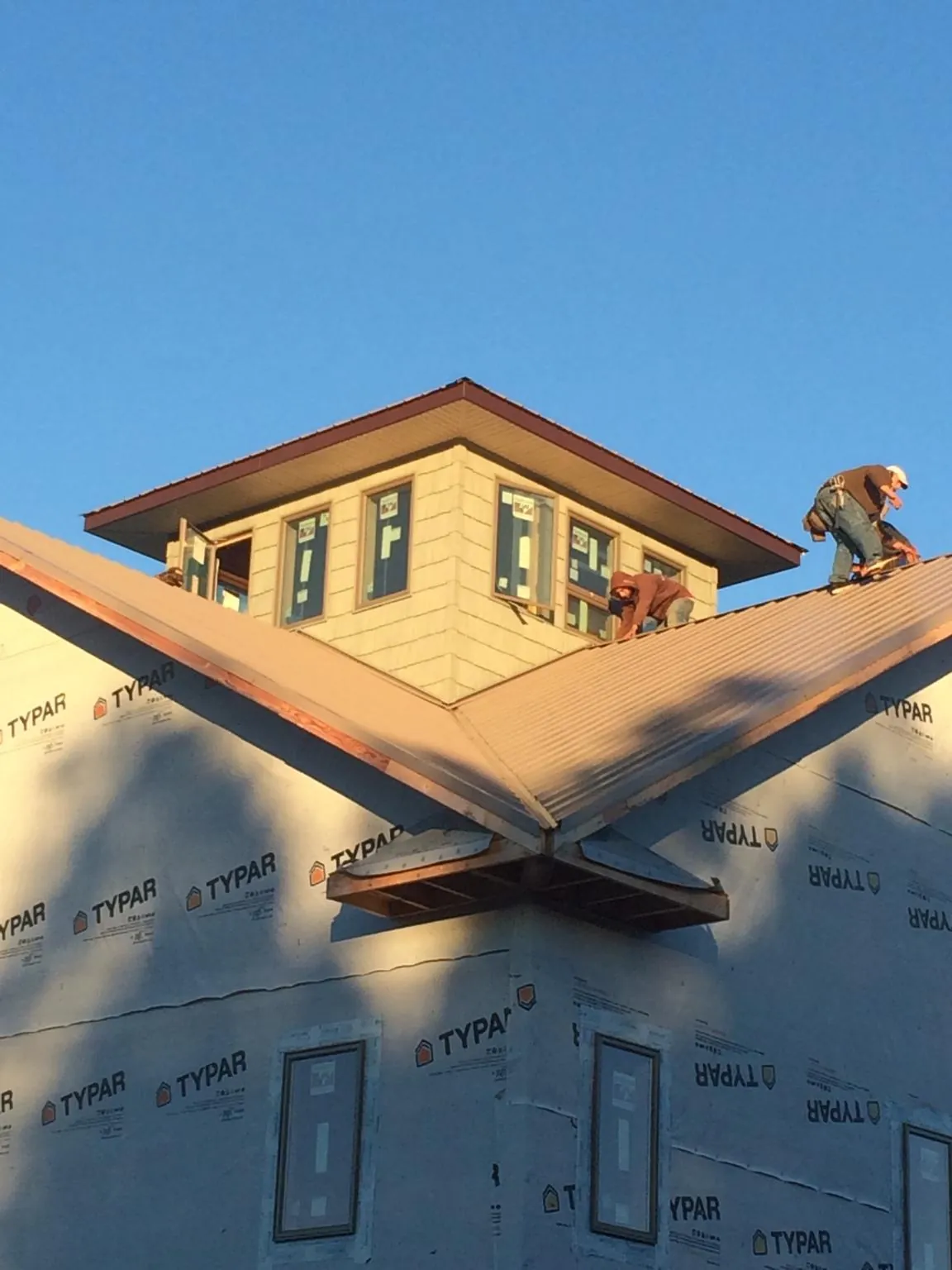 Roofers working around a rooftop cupola on a new metal roof at sunset — Roof Waterproofing in Manlius by Roofing Brothers